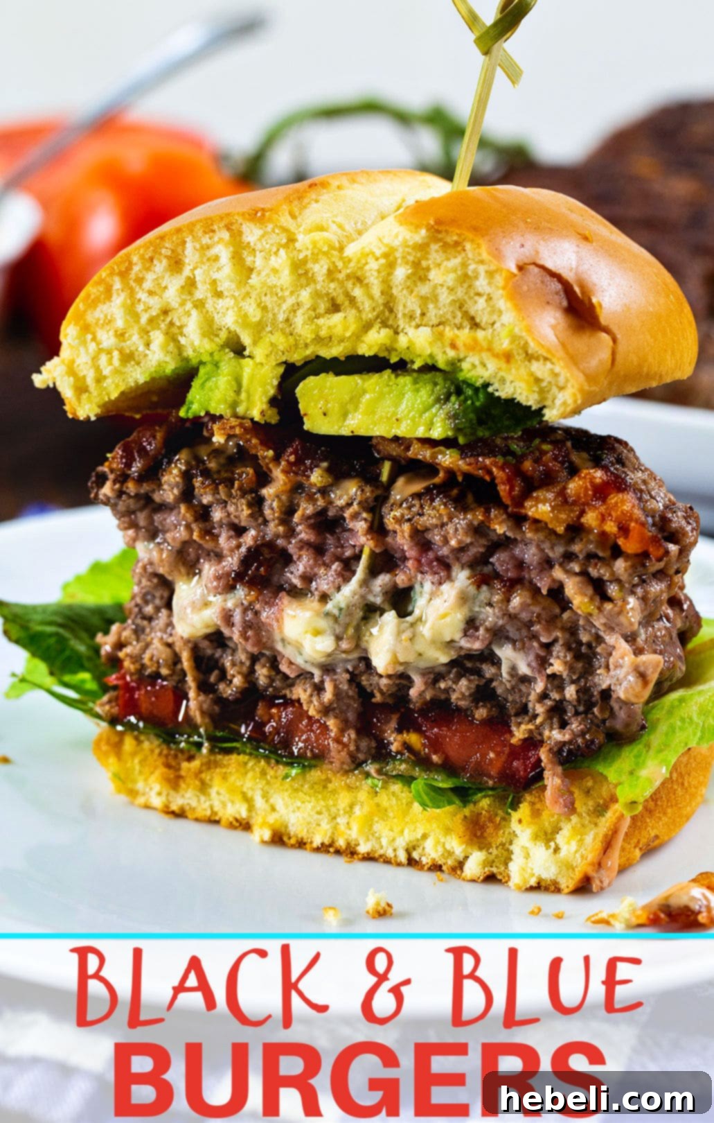 Finished Black and Blue Burger with toppings on a plate, cut in half.