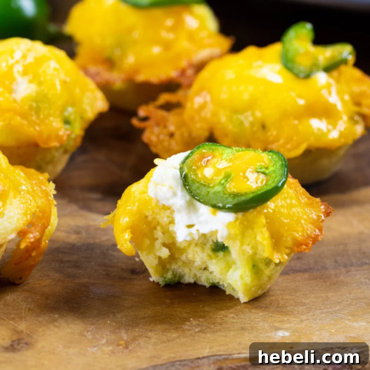 Jalapeno Cornbread Poppers 2 Jalapeno Popper Corn Muffins with bite taken out of one to show inside.
