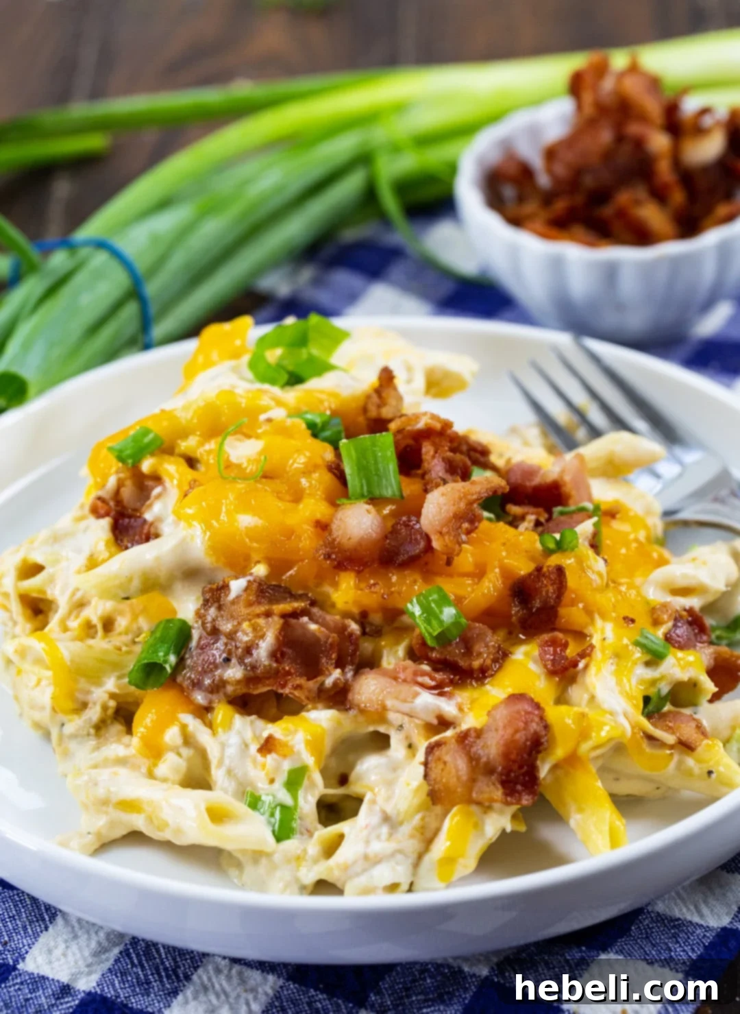 Addictive Slow Cooker Chicken Pasta 4 A generous serving of creamy Slow Cooker Crack Chicken Pasta dished up on a white plate, garnished with bacon and green onions.