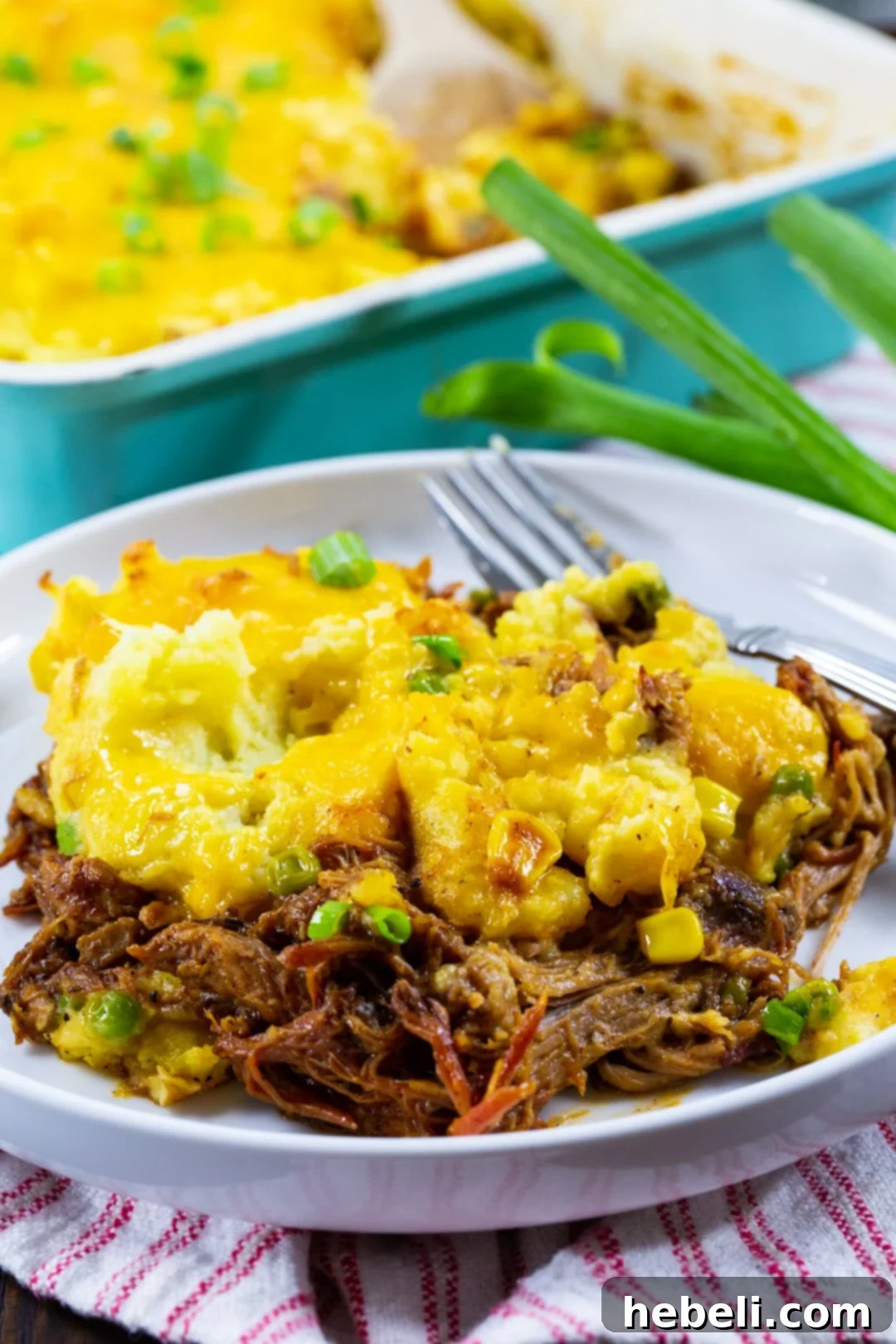 Hearty Pulled Pork Shepherds Pie 4 A generous serving of Pulled Pork Shepherd's Pie beautifully plated, ready to be enjoyed. The top layer of golden-brown mashed potatoes is visible, with the savory pork and vegetable filling peeking out from below.
