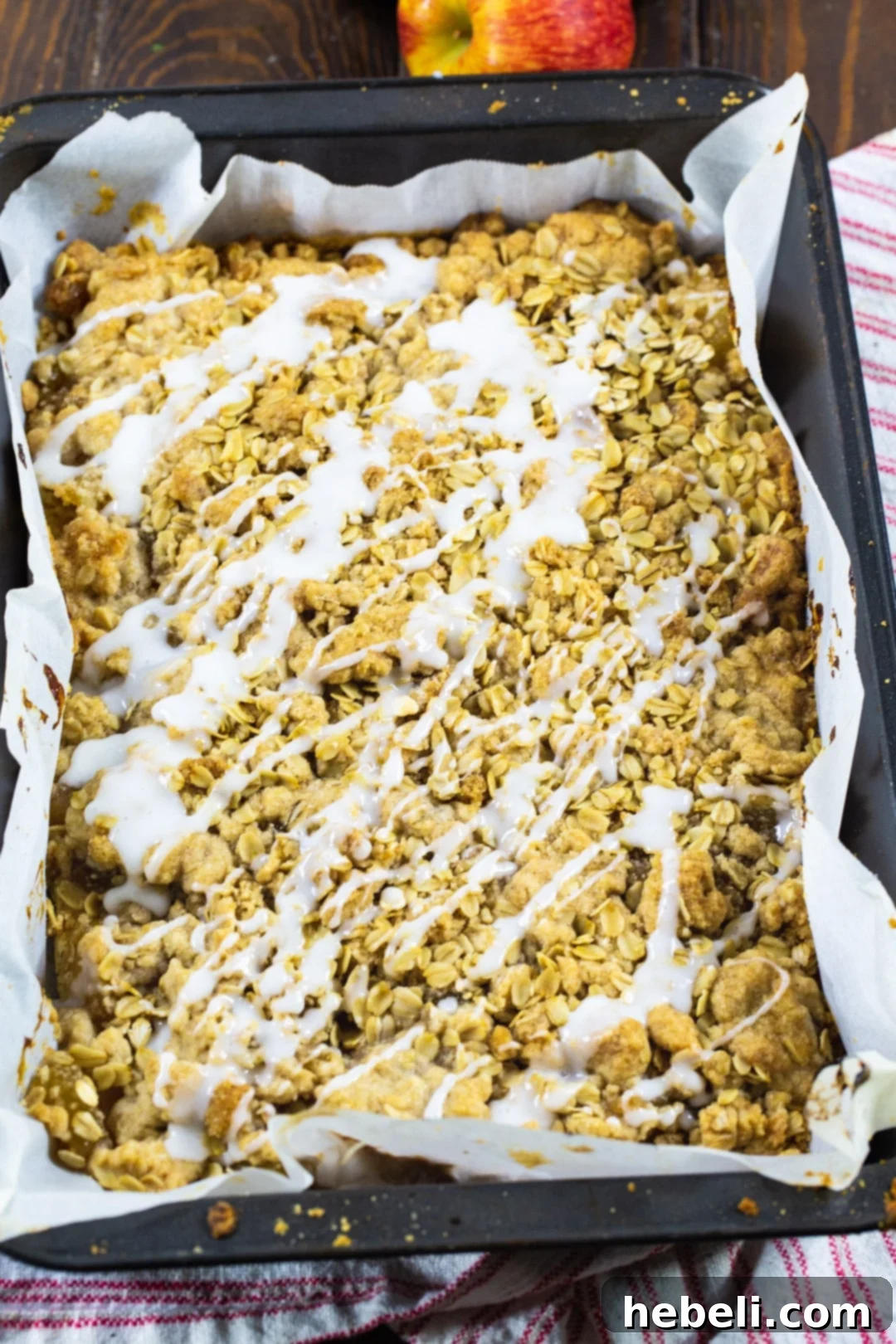 Freshly baked Oatmeal Crumb Apple Bars cooling in a 9x13-inch baking pan, showcasing their golden-brown topping.