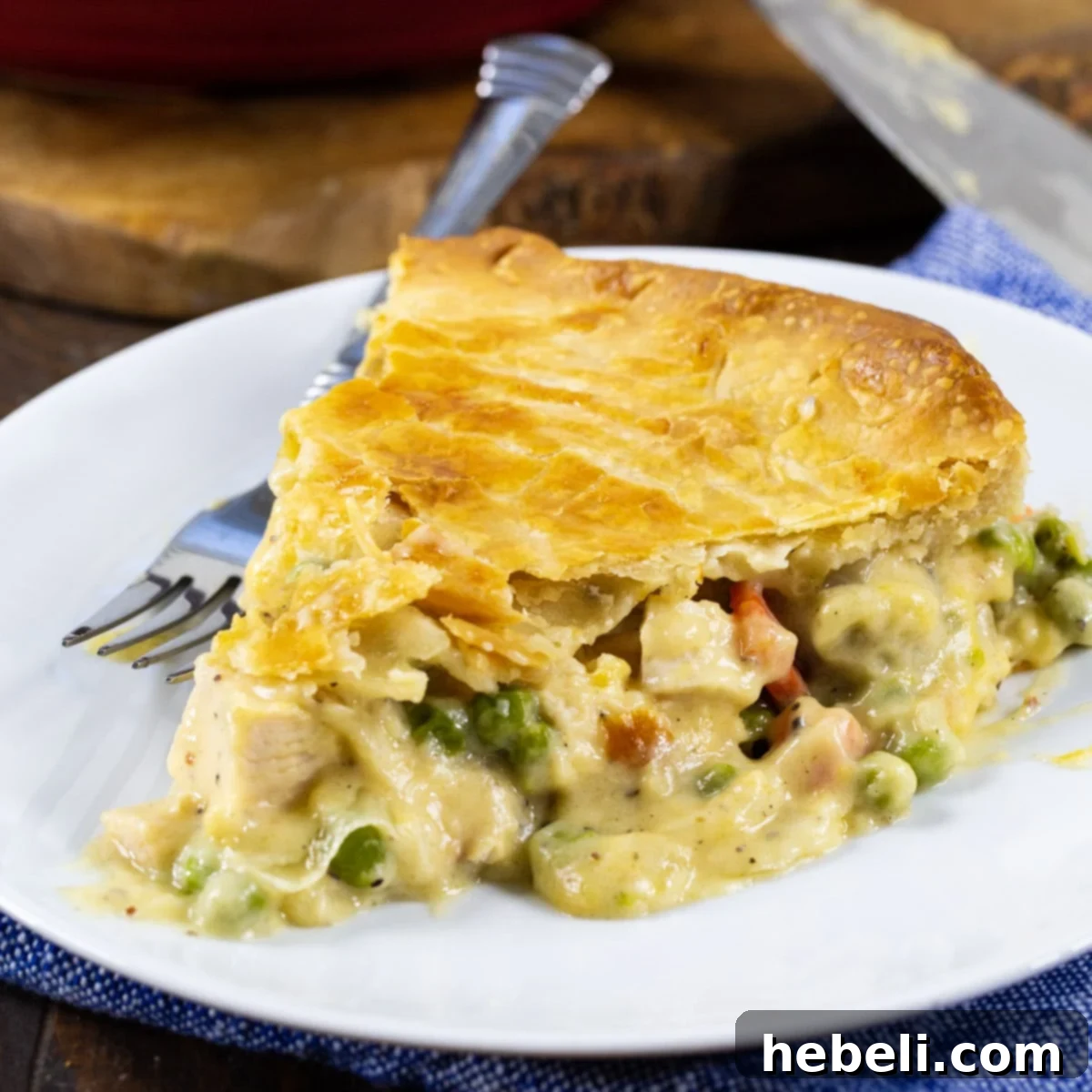 A perfectly golden slice of Cheesy Chicken Pot Pie on a white plate, showcasing its rich, creamy filling and flaky crust.