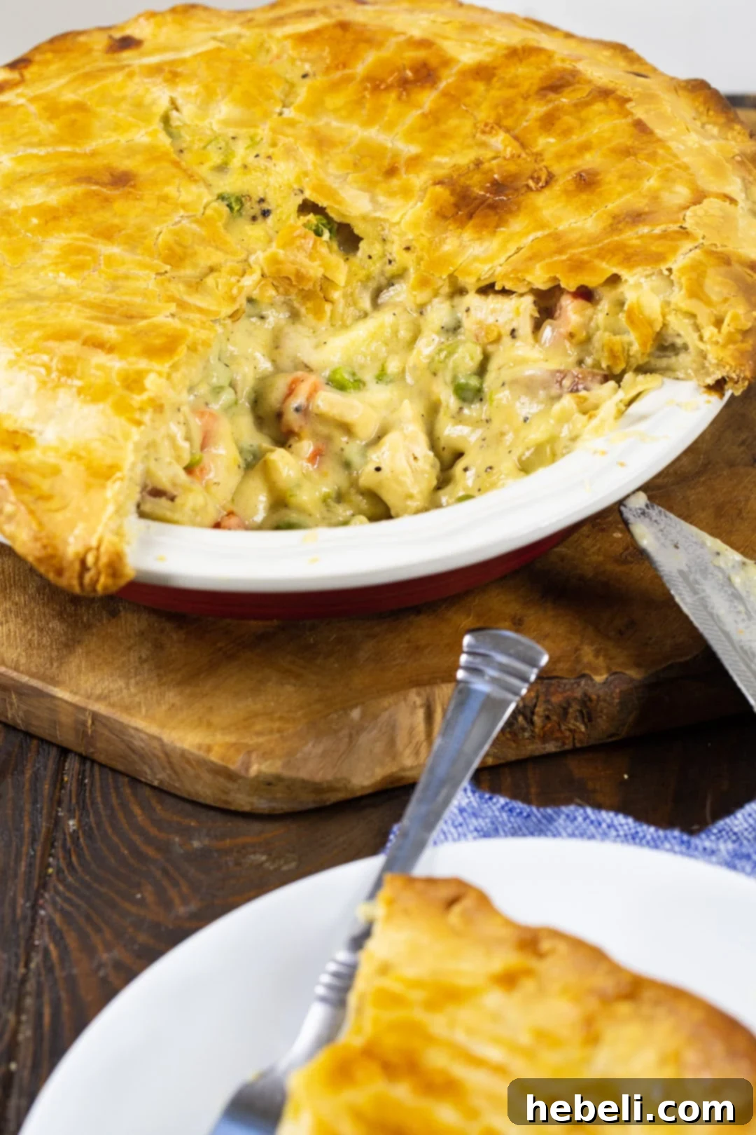 A freshly baked Cheesy Chicken Pot Pie in a pie pan, with a perfect slice cut out, revealing its rich and hearty cheesy filling.