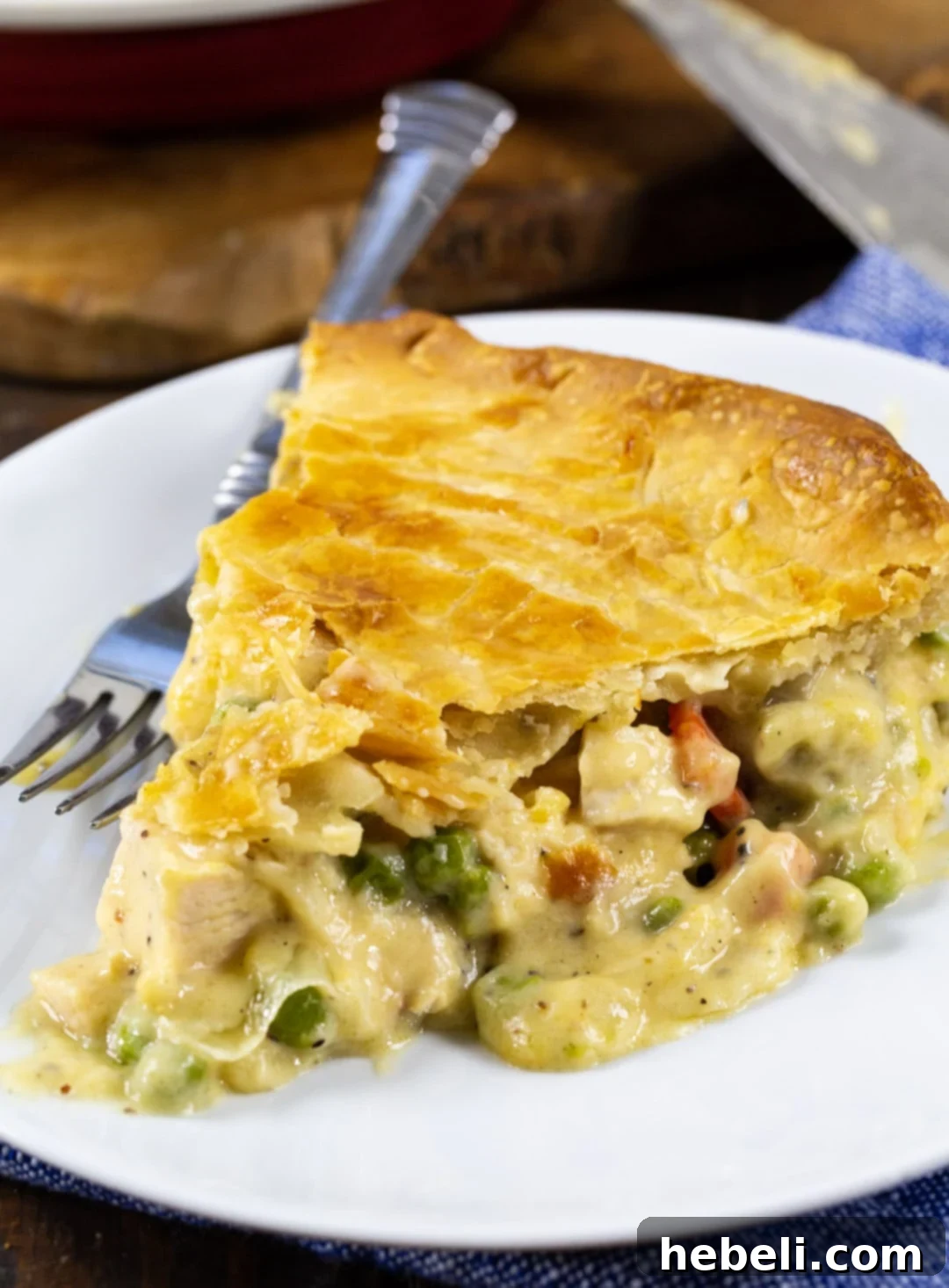 A close-up shot of a single slice of Cheesy Chicken Pot Pie, highlighting the thick, cheesy filling and the golden, flaky crust.