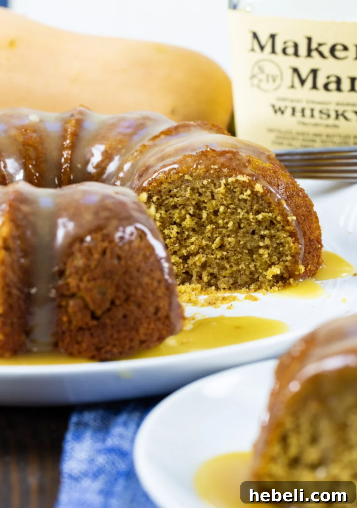 Fireside Butternut Bourbon Cake 4 A full Butternut Squash Cake with Bourbon Glaze, with a few slices already cut out, next to a bottle of bourbon.