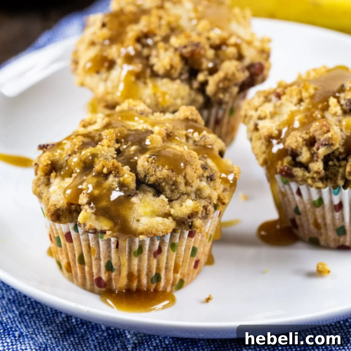 Irresistible Bananas Foster Muffins, generously drizzled with Rum Caramel Sauce and topped with streusel, presented beautifully on a plate.