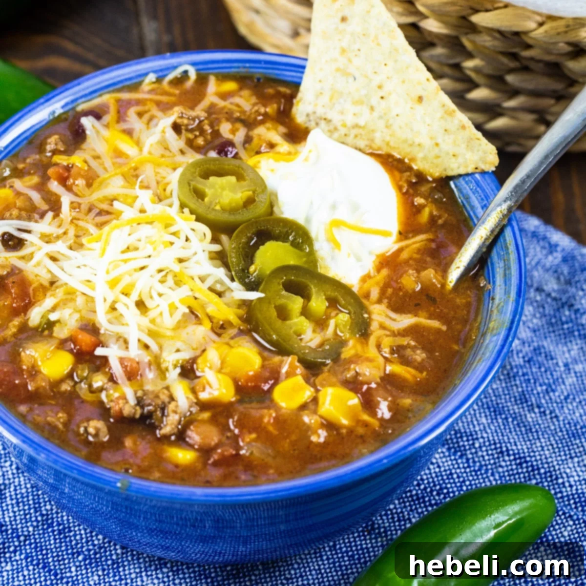 A vibrant bowl of homemade Taco Soup, garnished with fresh cilantro, shredded cheese, and a dollop of sour cream, set against a rustic background.