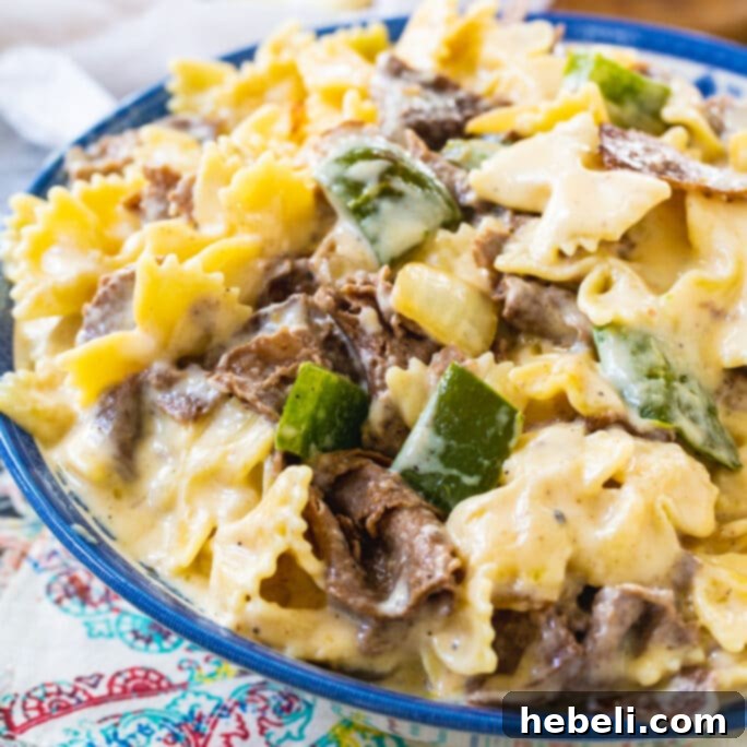 Ultimate Mac and Cheese Creations 6 Philly Cheesesteak Mac and Cheese in a vibrant blue and white bowl, ready to be enjoyed with its meaty and cheesy goodness.