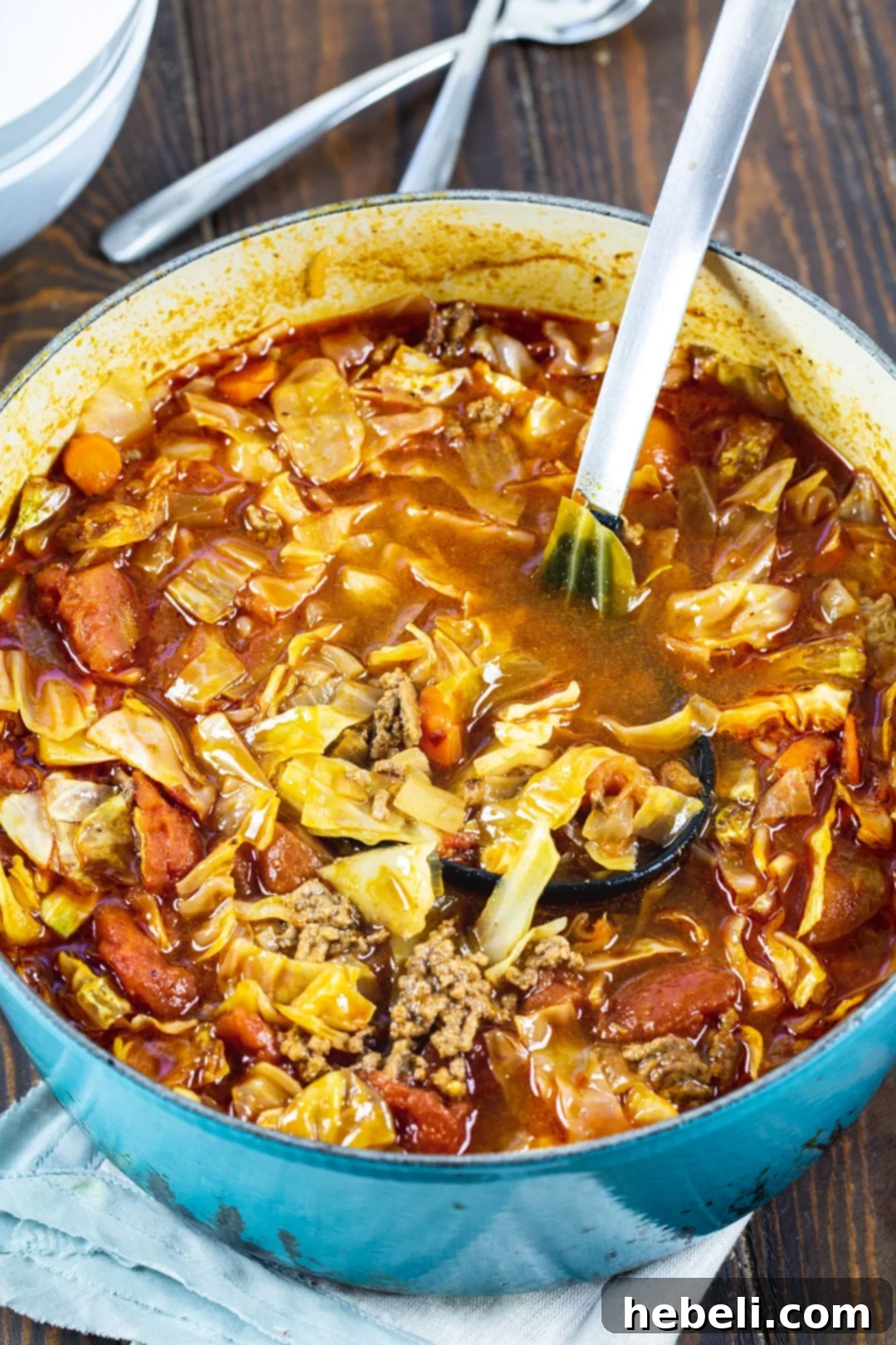 Spicy Tex-Mex Cabbage Soup 3 A spoon scooping a generous portion of Tex-Mex Cabbage Soup from a Dutch oven, highlighting the rich ingredients.