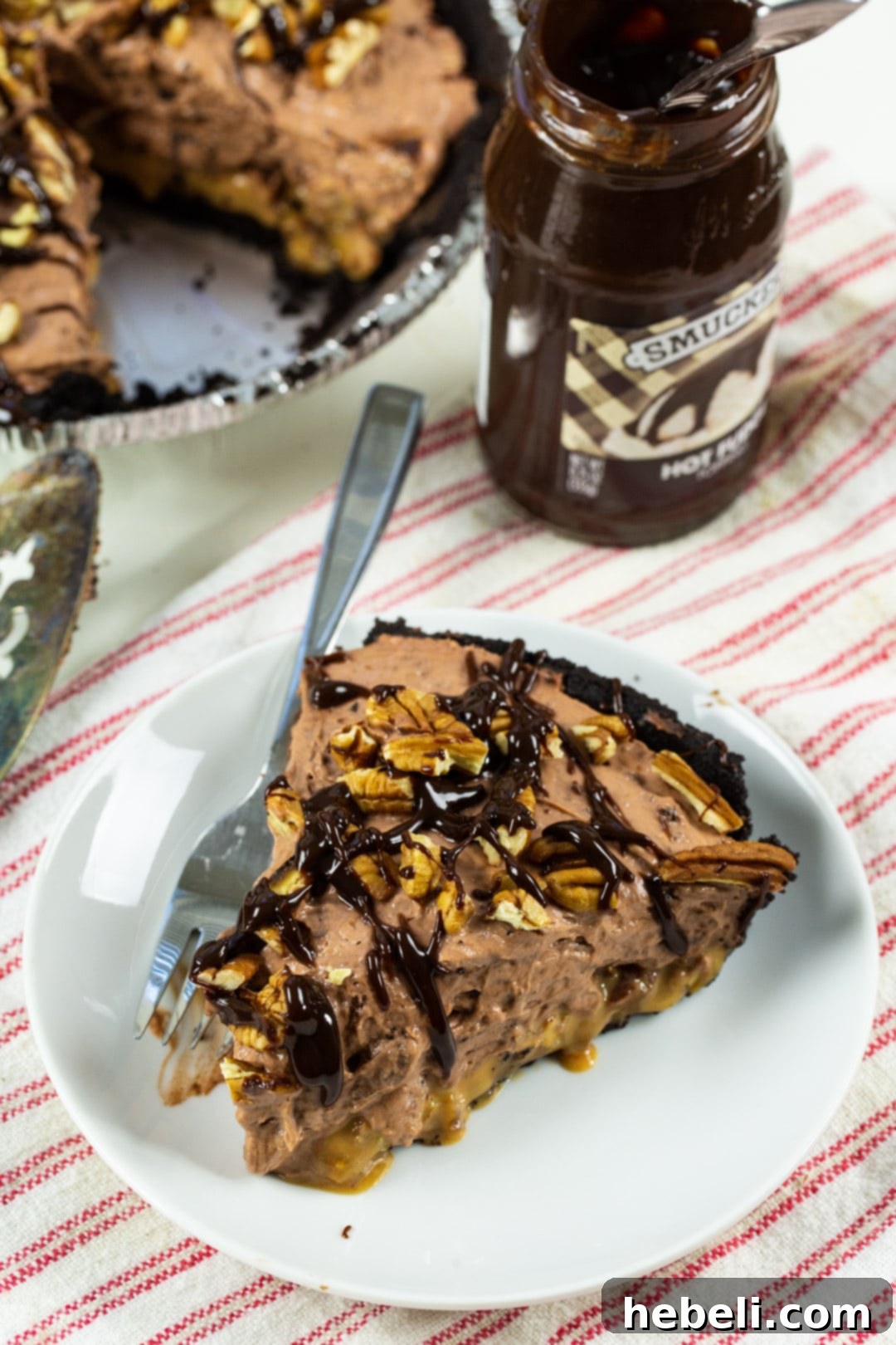 Decadent Chocolate Caramel Dream 3 A close-up of a pie slice, generously drizzled with rich fudge sauce and sprinkled with pecans.