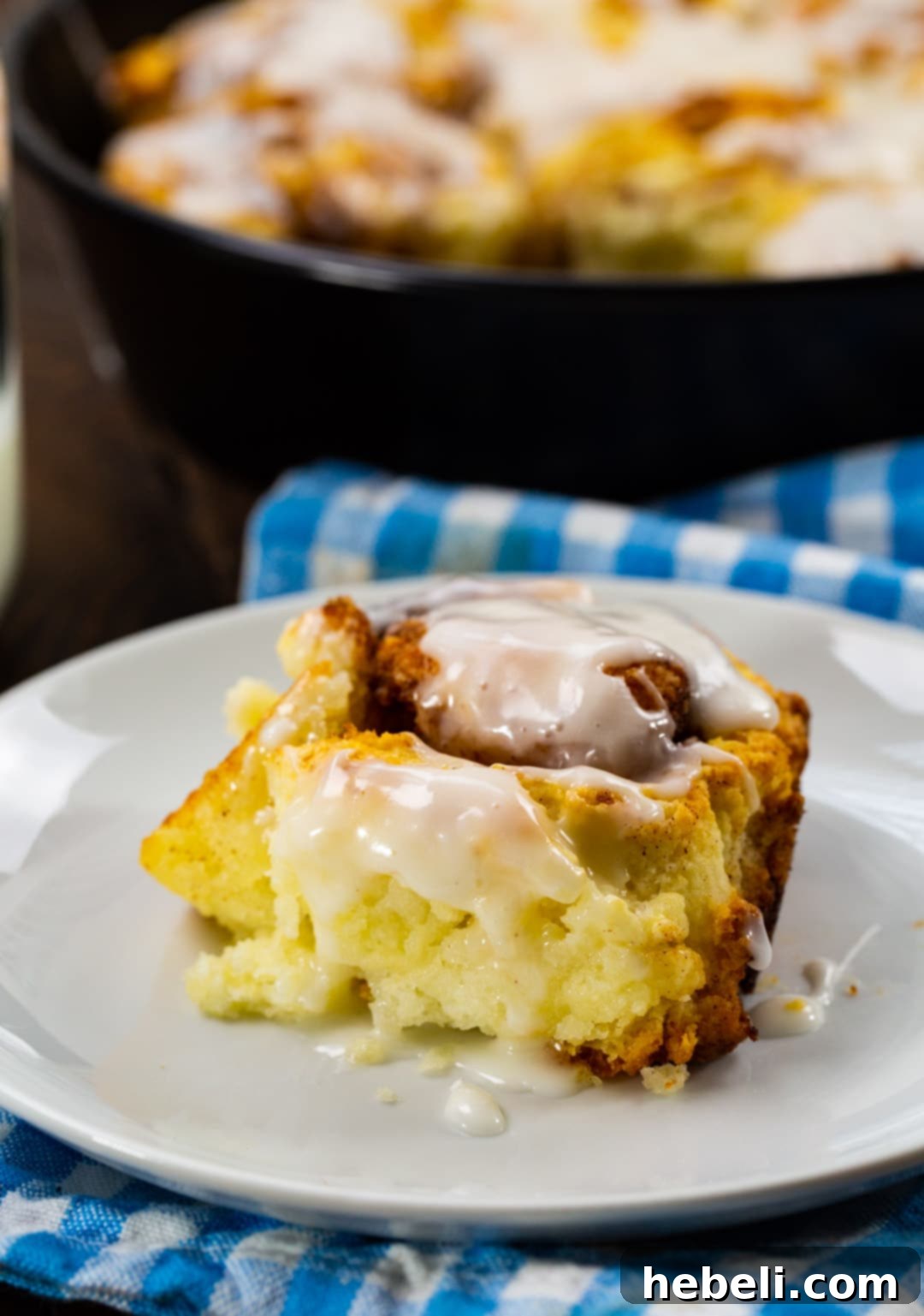 Fluffy Buttermilk Biscuit Cinnamon Rolls 4 A single Buttermilk Biscuit Cinnamon Roll, generously glazed, resting on a white plate with a fork.