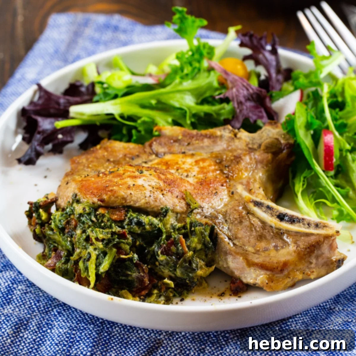 Perfectly cooked Spinach and Bacon Stuffed Pork Chops on a pristine white plate, garnished with fresh herbs.