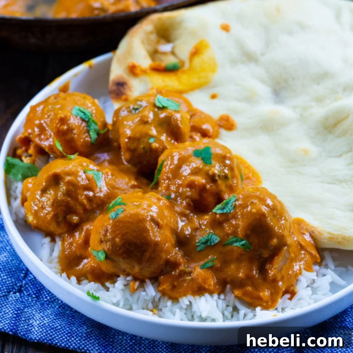 Butter Chicken Meatballs over rice on a plate.