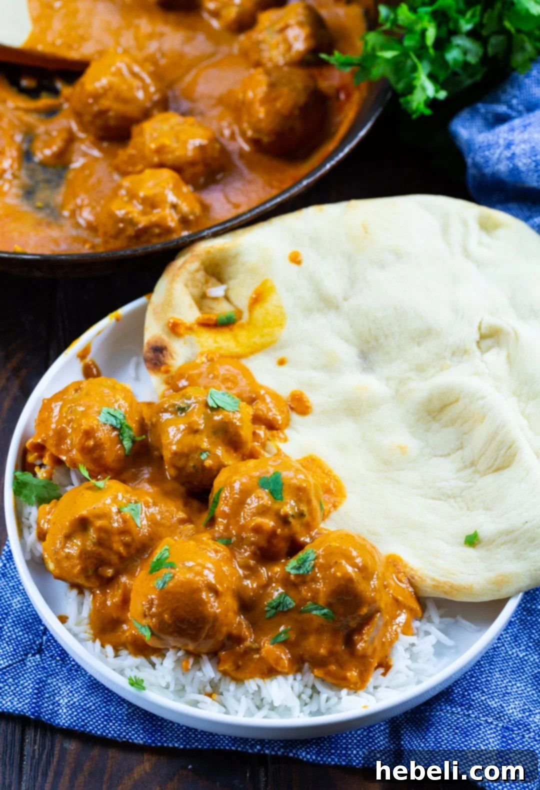 Butter Chicken Meatballs on a plate with naan and skillet full of meatballs.