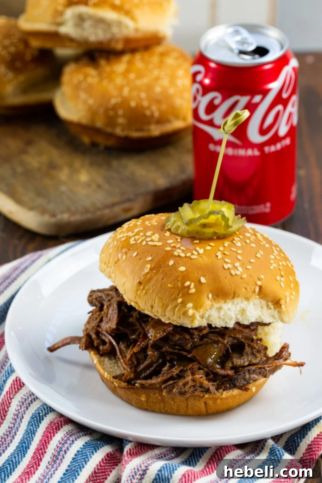 Slow Cooker BBQ Beef on a bun with a can of Coke in the background.
