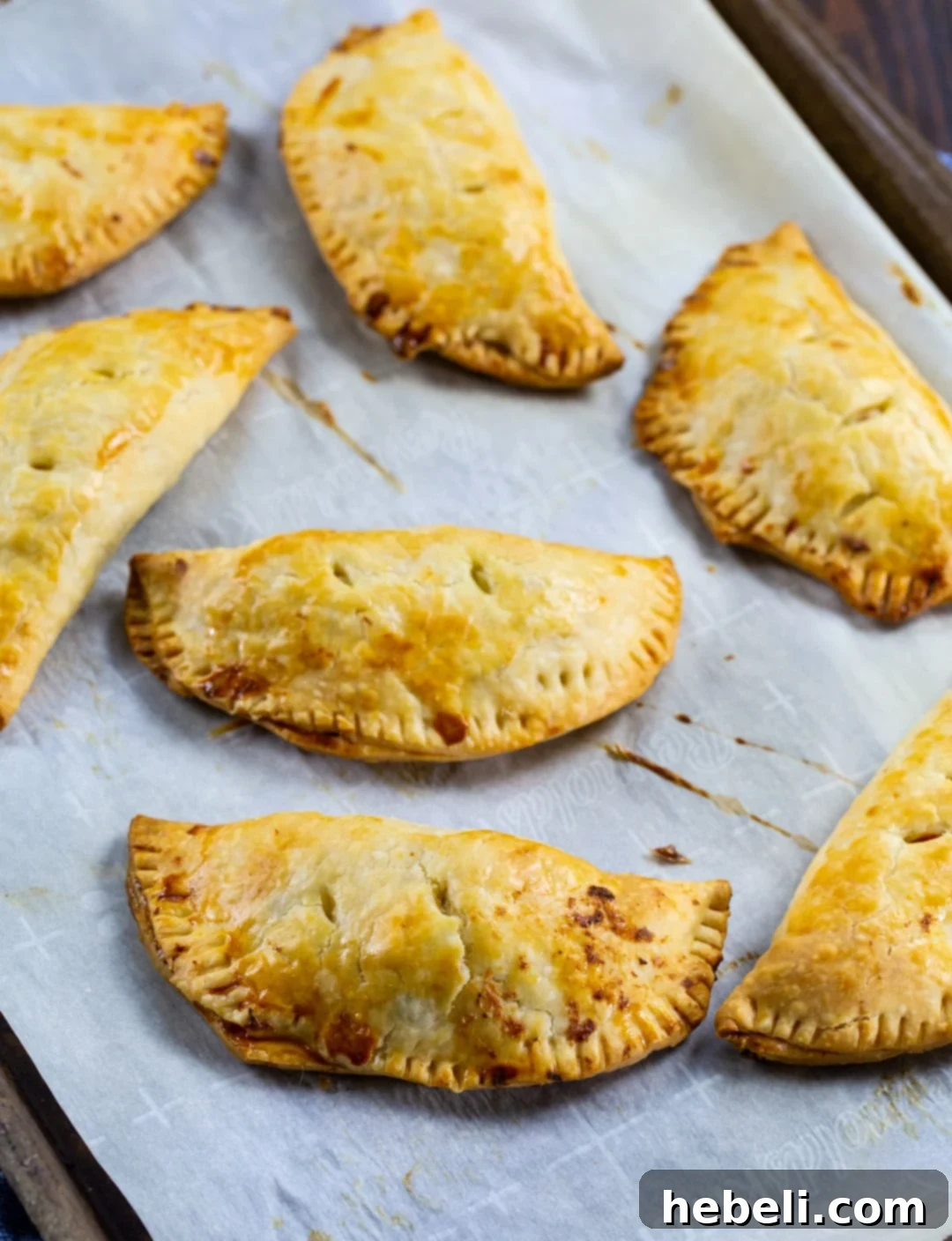 Creamy Chicken Pockets 3 Several unbaked Creamy Chicken Hand Pies arranged on a parchment paper-lined baking sheet, showing their neat half-moon shape before baking.