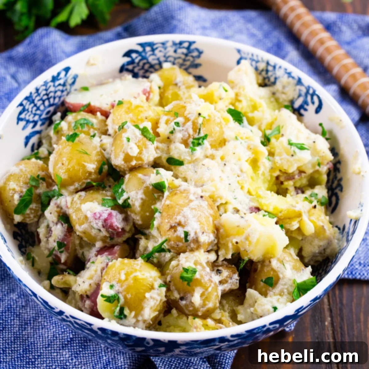 A close-up shot of creamy Sour Cream New Potatoes garnished with fresh dill in a white serving bowl.