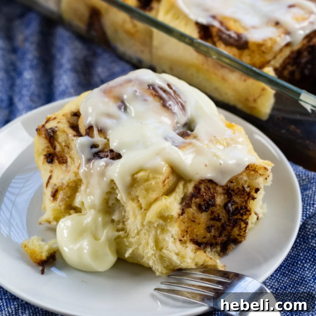 Luscious Nutella Cinnamon Buns 2 A single Nutella Cinnamon Roll on a small white plate, showcasing its soft texture and generous glaze.