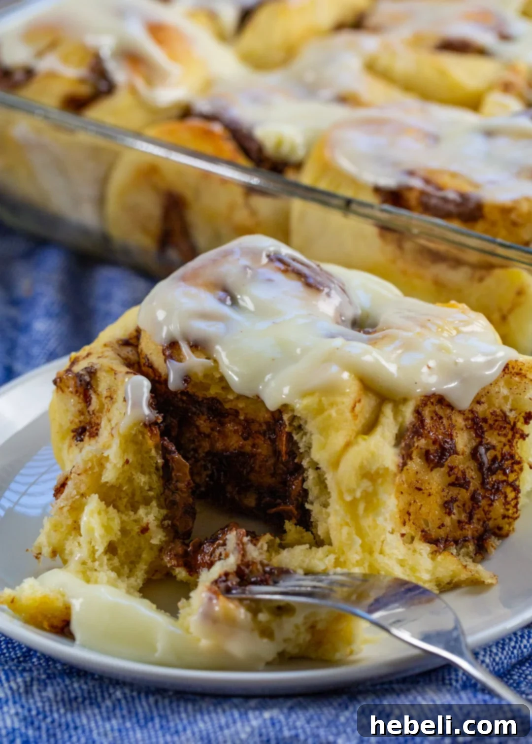 Luscious Nutella Cinnamon Buns 5 A fork gently cutting into a warm, soft Nutella Cinnamon Roll, revealing its gooey center and tender layers.