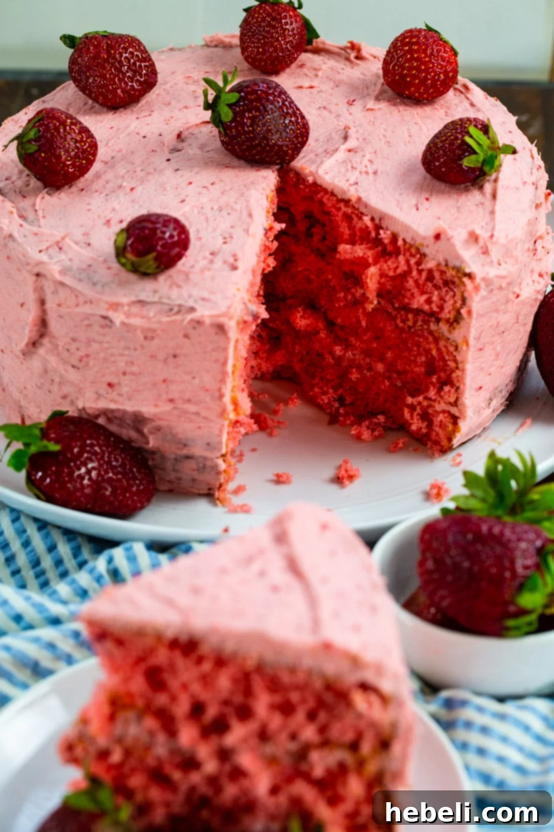 Strawberry Layer Cake with a slice removed, showing off the perfectly layered cake and creamy frosting.