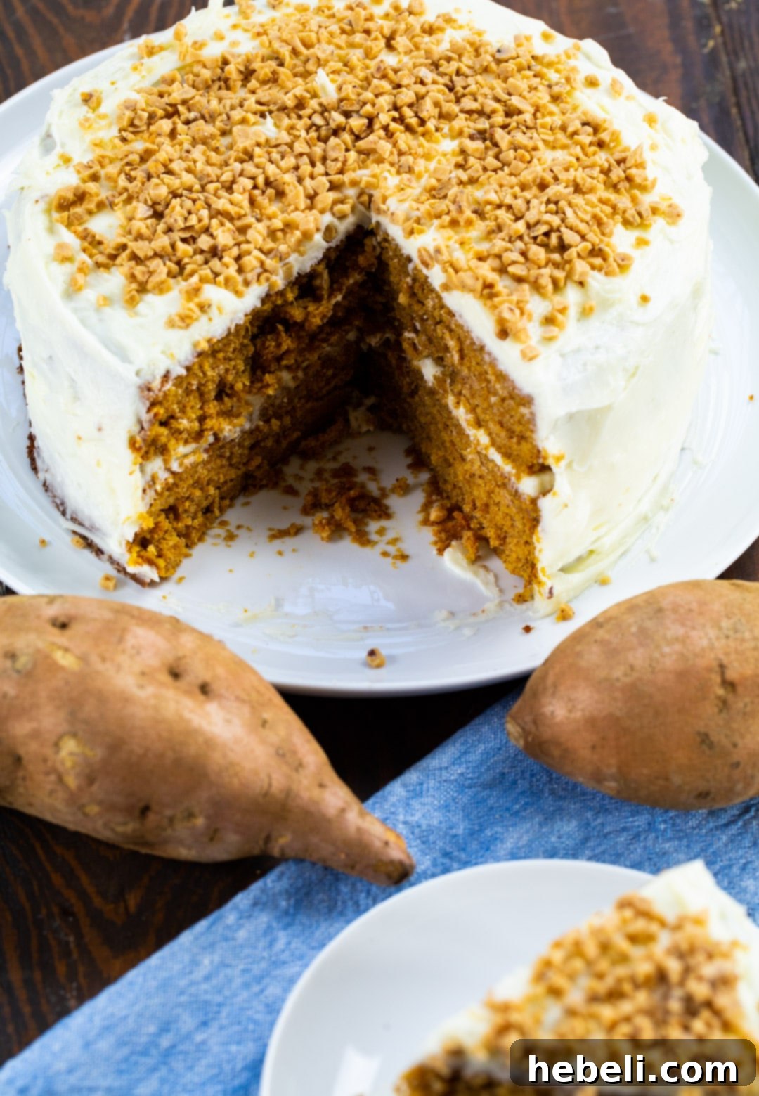 Velvet Sweet Potato Cake 3 A stunning Sweet Potato Layer Cake displayed on a cake stand, with one slice elegantly removed, revealing its soft layers and creamy frosting.