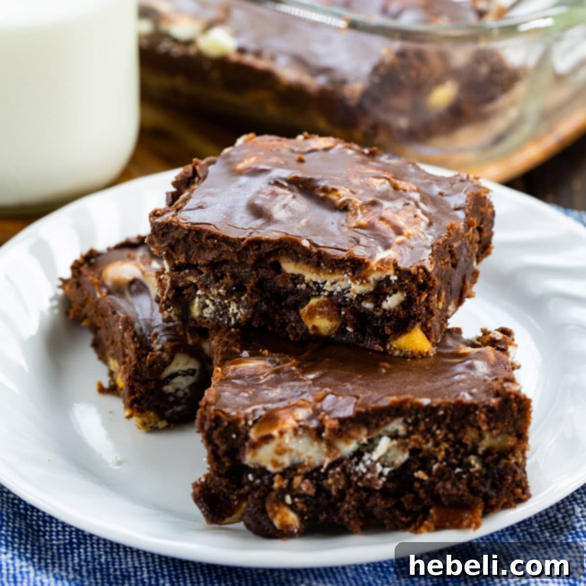 Tuxedo Brownies 2 Three Black and White Brownies on a plate, showcasing the contrast between the dark brownie base and the white chocolate chips, topped with a rich chocolate frosting.