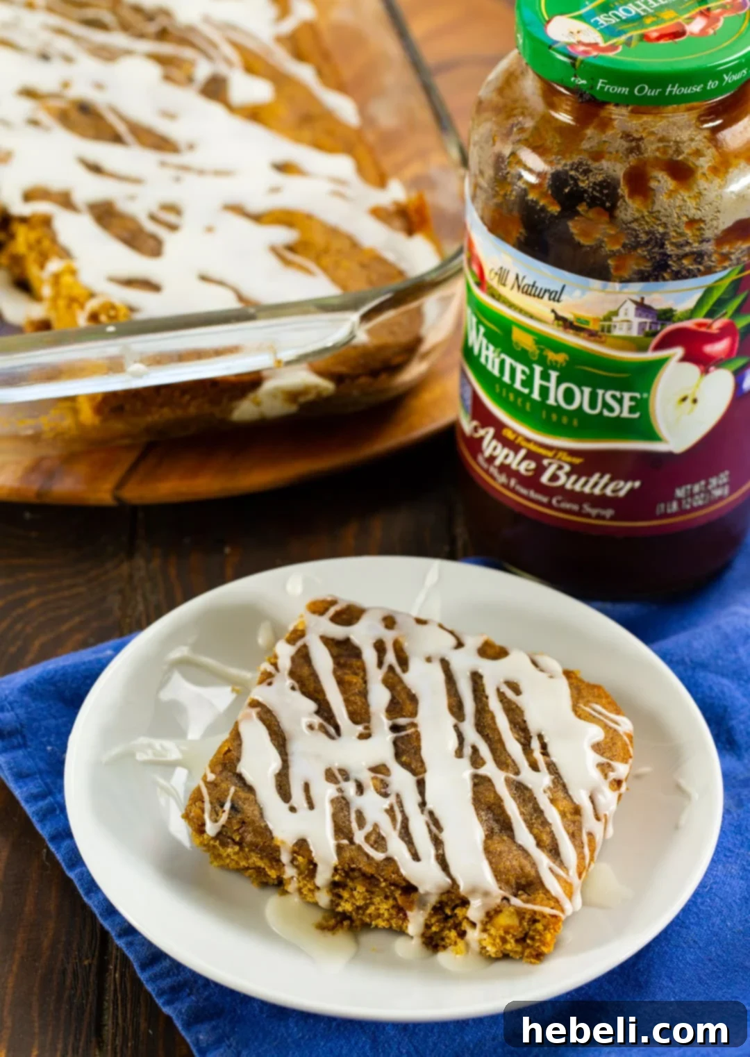 An Apple Butter Bar resting on a white plate, with a jar of homemade apple butter in the background, symbolizing its key ingredient.