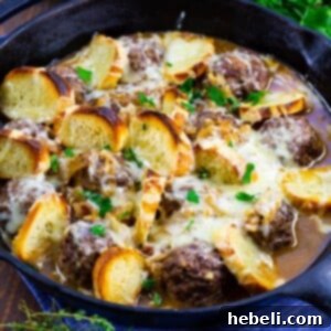 A close-up of French Onion Meatballs with melted cheese and gravy.