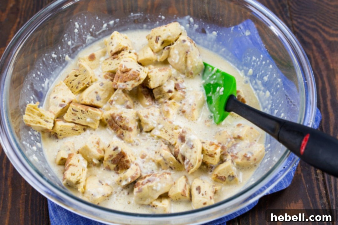Biscuit pieces mixed with a creamy cream cheese mixture in a bowl.