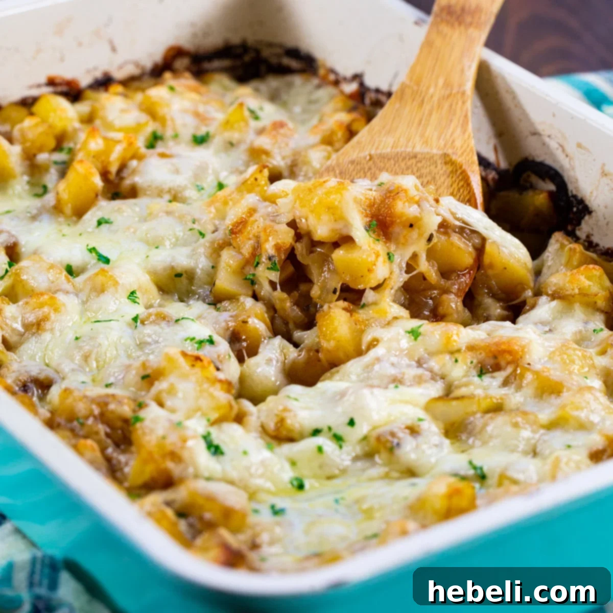 Spoon scooping French Onion Potatoes out of baking dish.