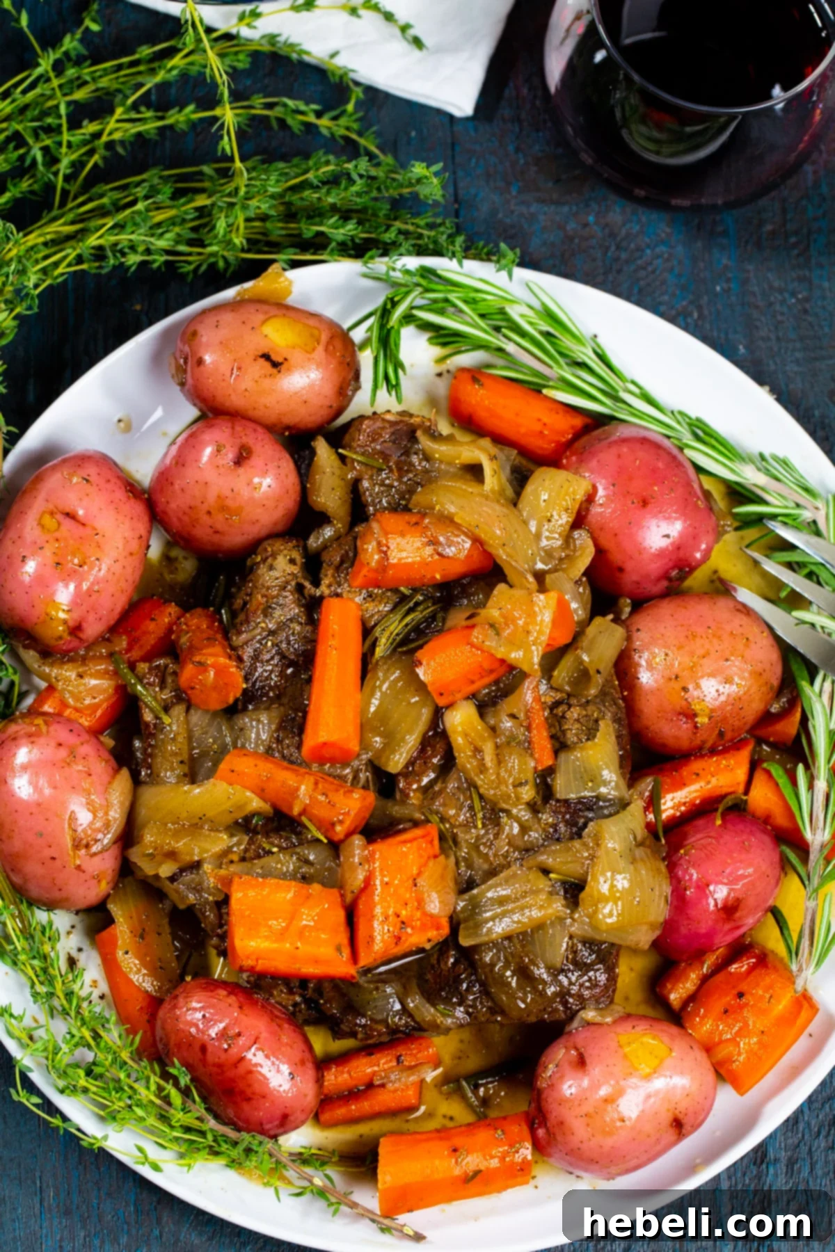 Perfectly Tender Pot Roast 4 Pot Roast on serving plate with fresh herbs.