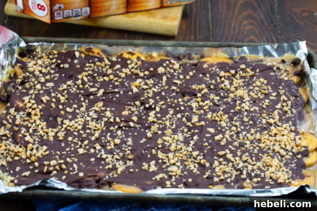 The baking sheet reveals a freshly baked batch of Ritz Cracker Toffee, with the rich, melted chocolate expertly spread over the warm, golden toffee layer, awaiting its final cooling.