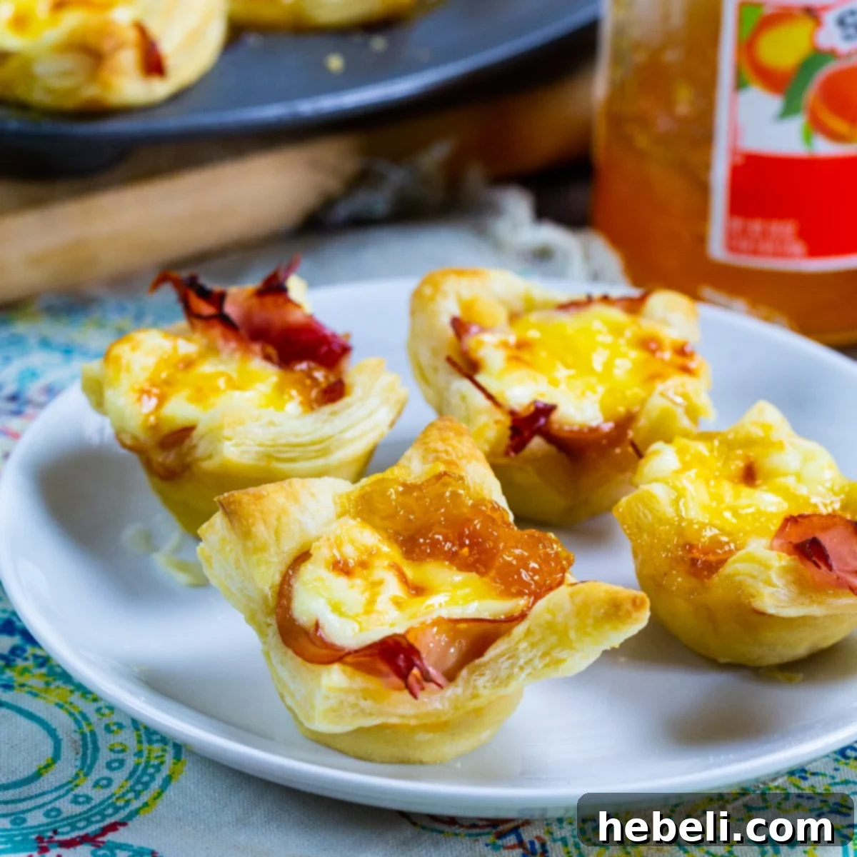 Golden Ham and Brie Pastry Bites 2 Ham and Brie Puff Pastry Cups on a plate.