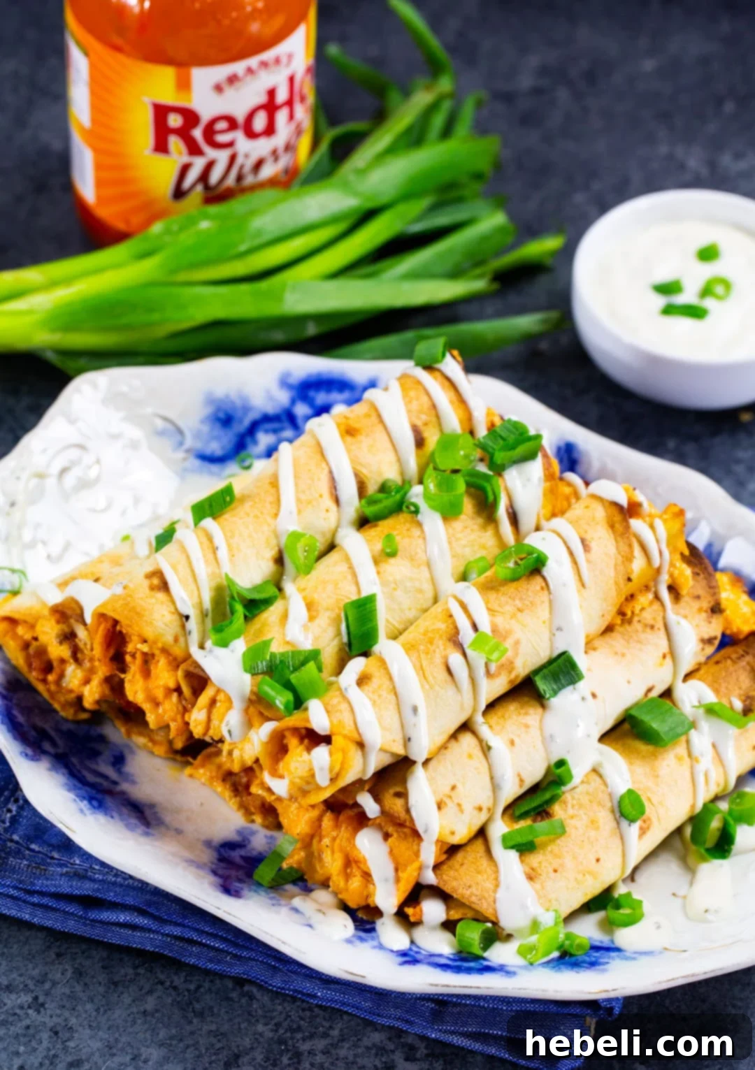 Buffalo Chicken Taquitos Served with Ranch A close-up of baked Buffalo Chicken Taquitos alongside a bowl of creamy ranch dipping sauce.
