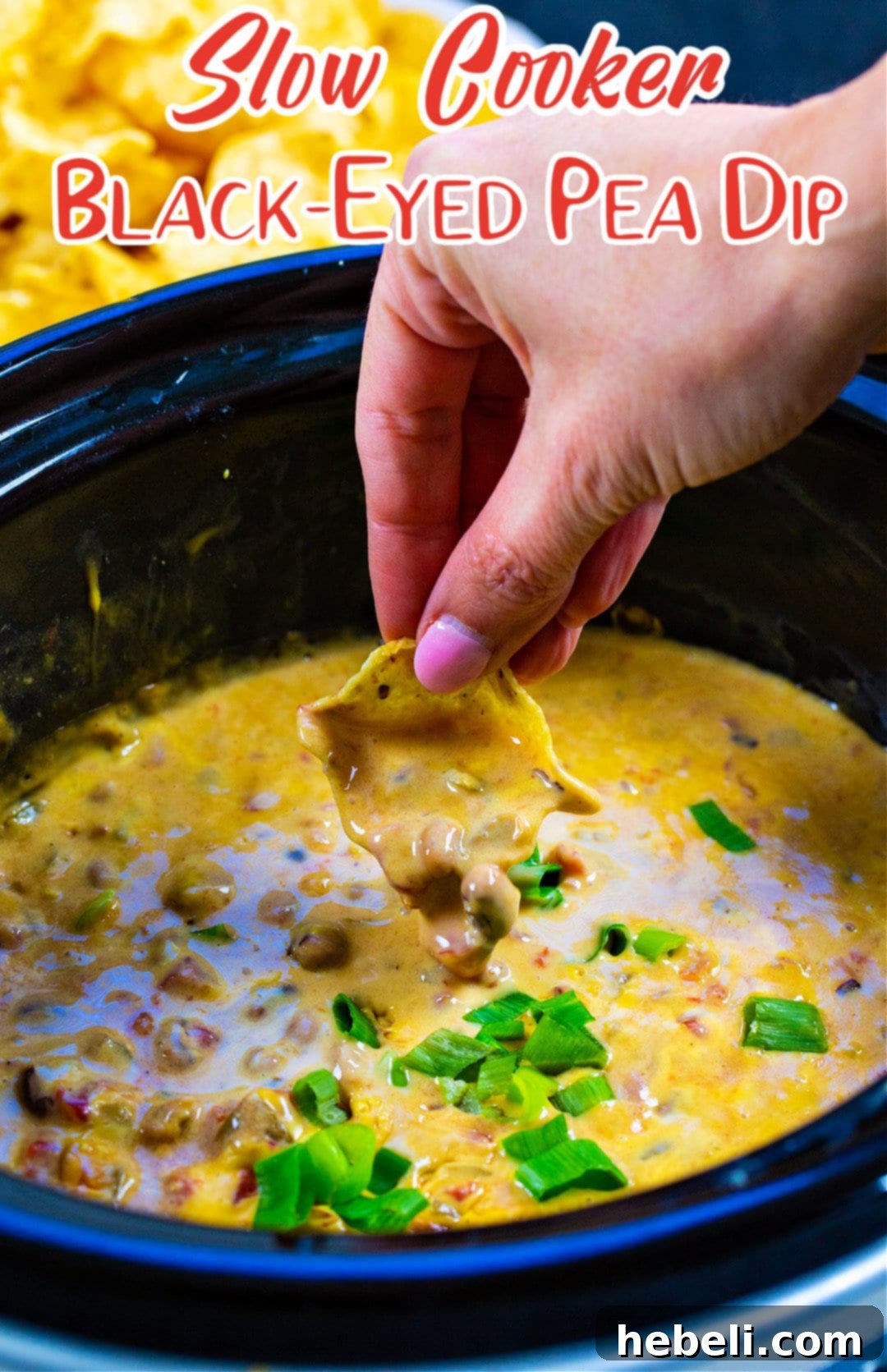 Chip being dipped into a warm, creamy Slow Cooker Black-Eyed Pea Dip.