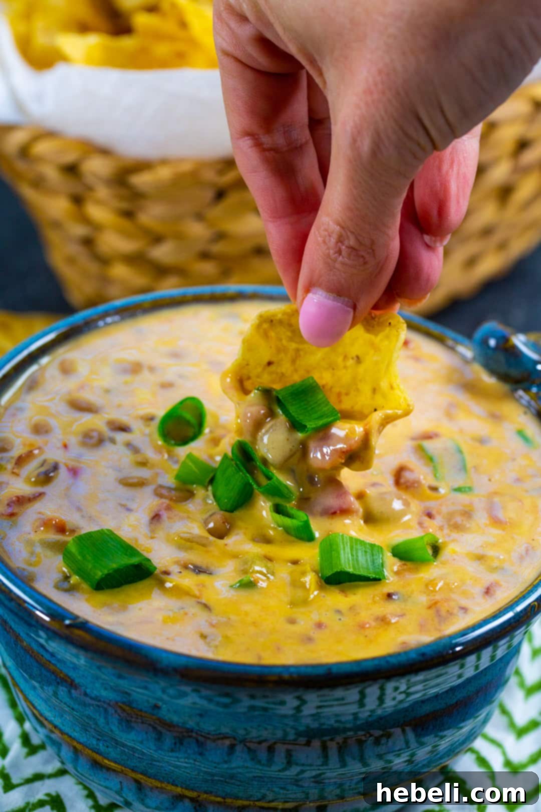 Another image of a hand dipping a chip into the delicious Slow Cooker Black-Eyed Pea Dip.