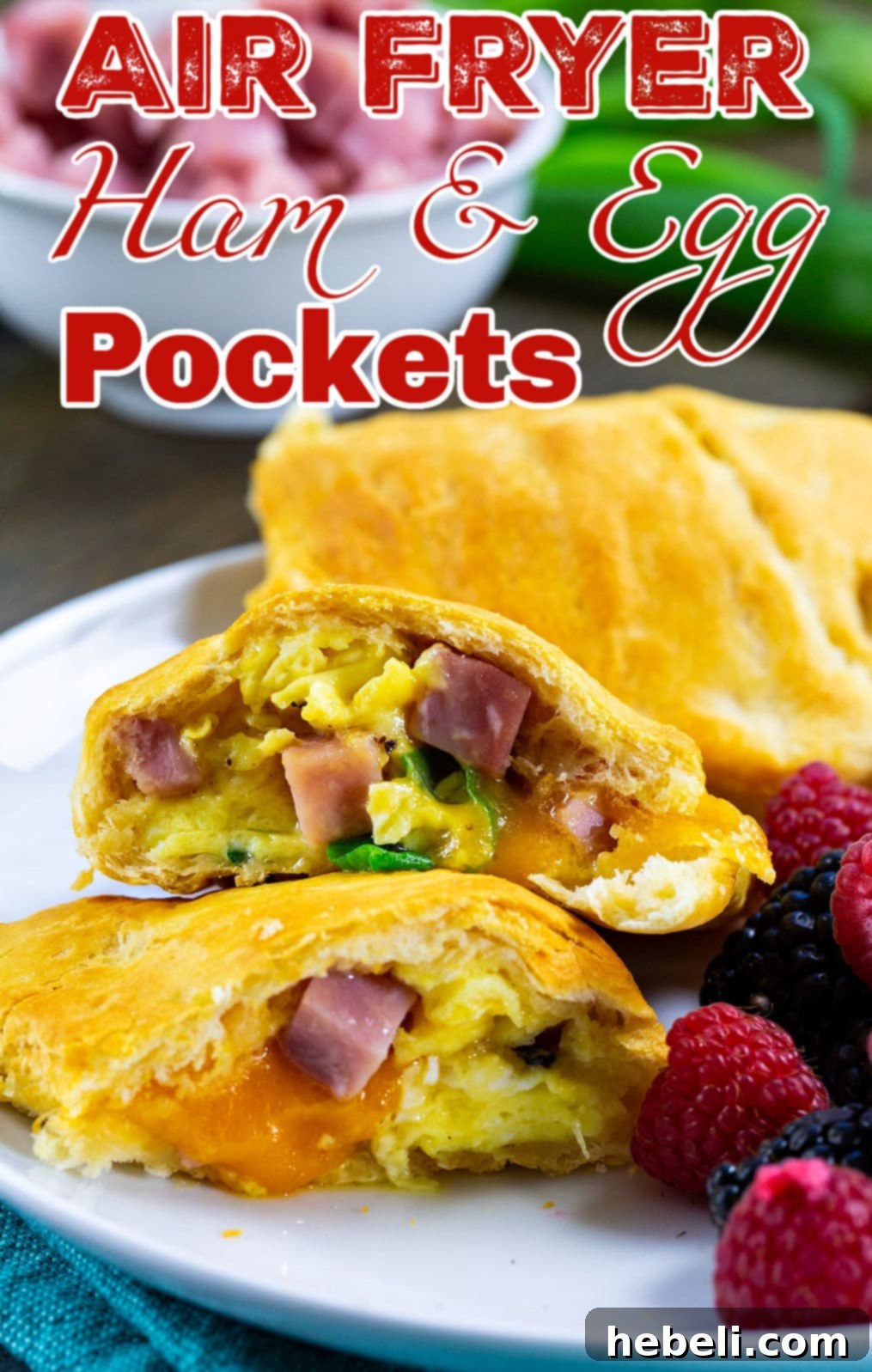Air Fryer Ham and Egg Bundles 5 Beautifully cooked Air Fryer Ham and Egg Pockets on a plate, garnished with fresh fruit, ready to be enjoyed.