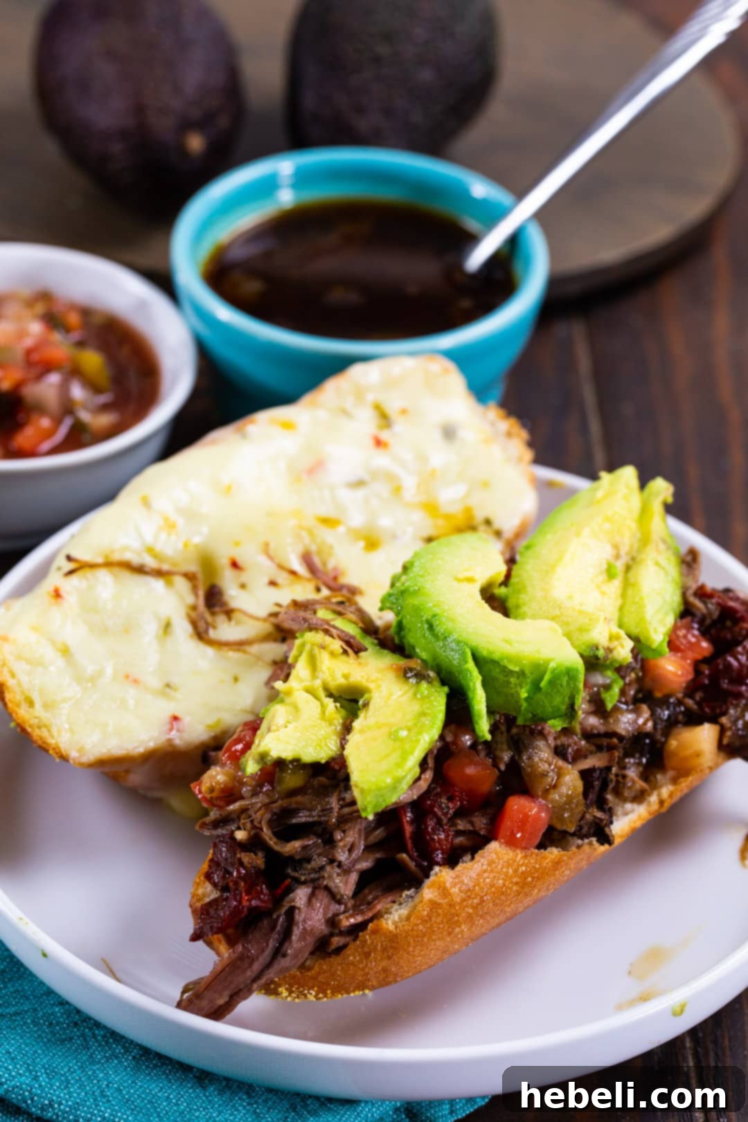 Sandwich on a plate and a bowl of Au Jus.