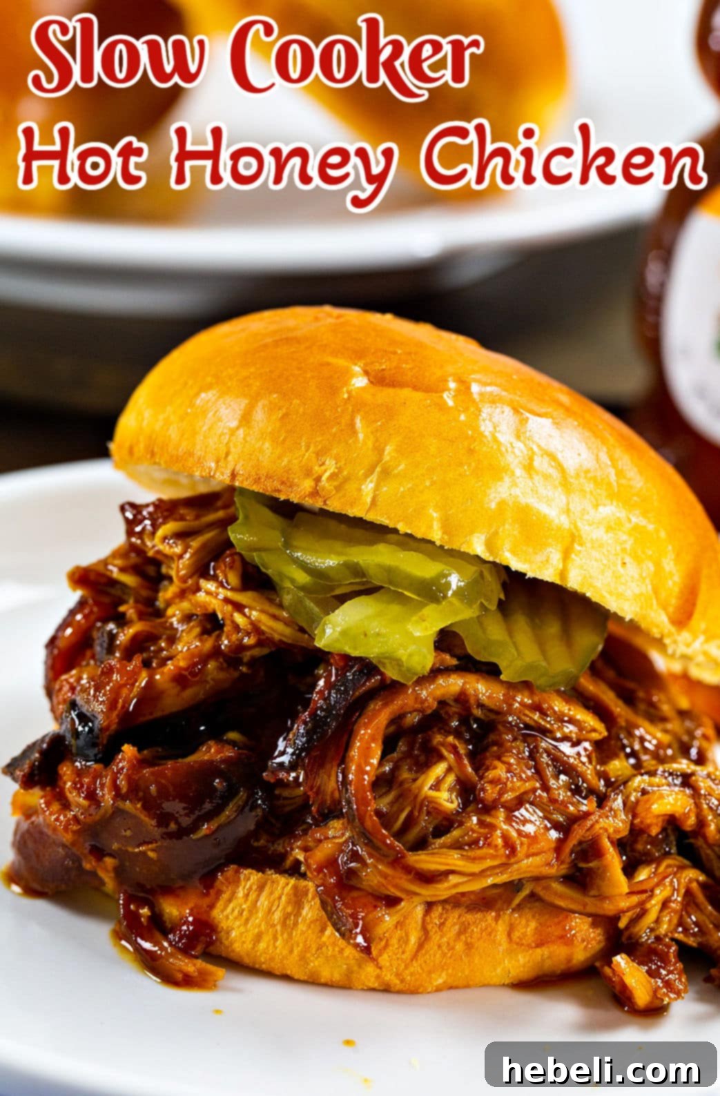 Slow Cooker Hot Honey Chicken on a bun with pickles, a complete and appetizing meal.