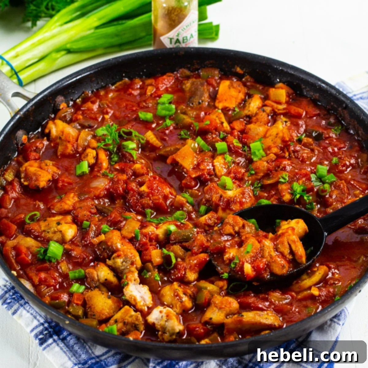 Chicken Creole bubbling in a skillet, showcasing rich red sauce and tender chicken.