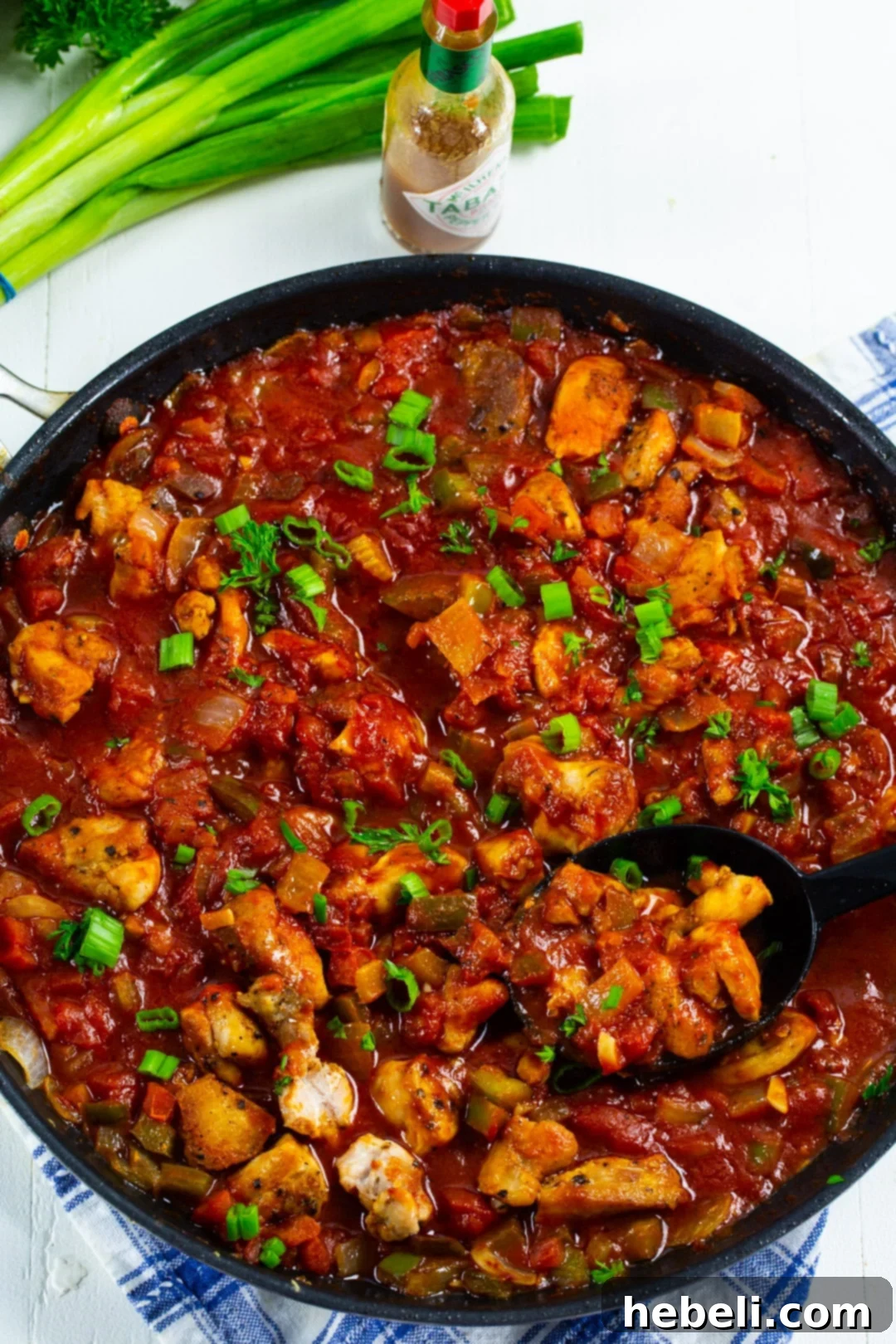 Close-up of the finished Chicken Creole dish, garnished with fresh herbs, in a large skillet.