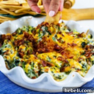 Close-up of baked Collards Artichoke Dip in a baking dish, garnished with fresh herbs and crumbled bacon.