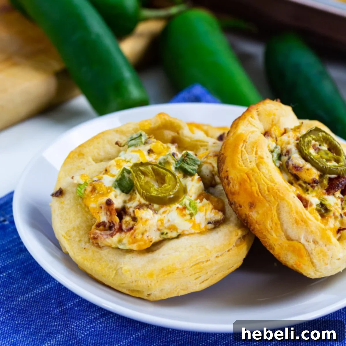 Two Jalapeno Popper Biscuit Rounds on a plate, showcasing their golden-brown edges and creamy topping.