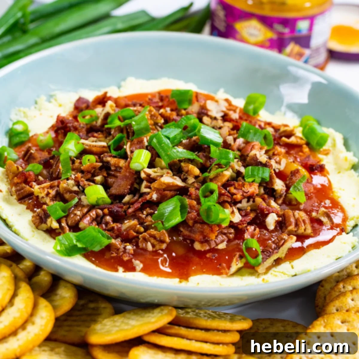 Tropical Tango Cheese Dip 2 A vibrant bowl of Cheese Dip with Mango Chutney, garnished with fresh herbs and surrounded by an assortment of crisp crackers, ready to be served at a party.