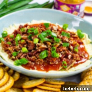 Cheese Dip with Mango Chutney in a small white bowl, garnished with green onions and surrounded by crackers.