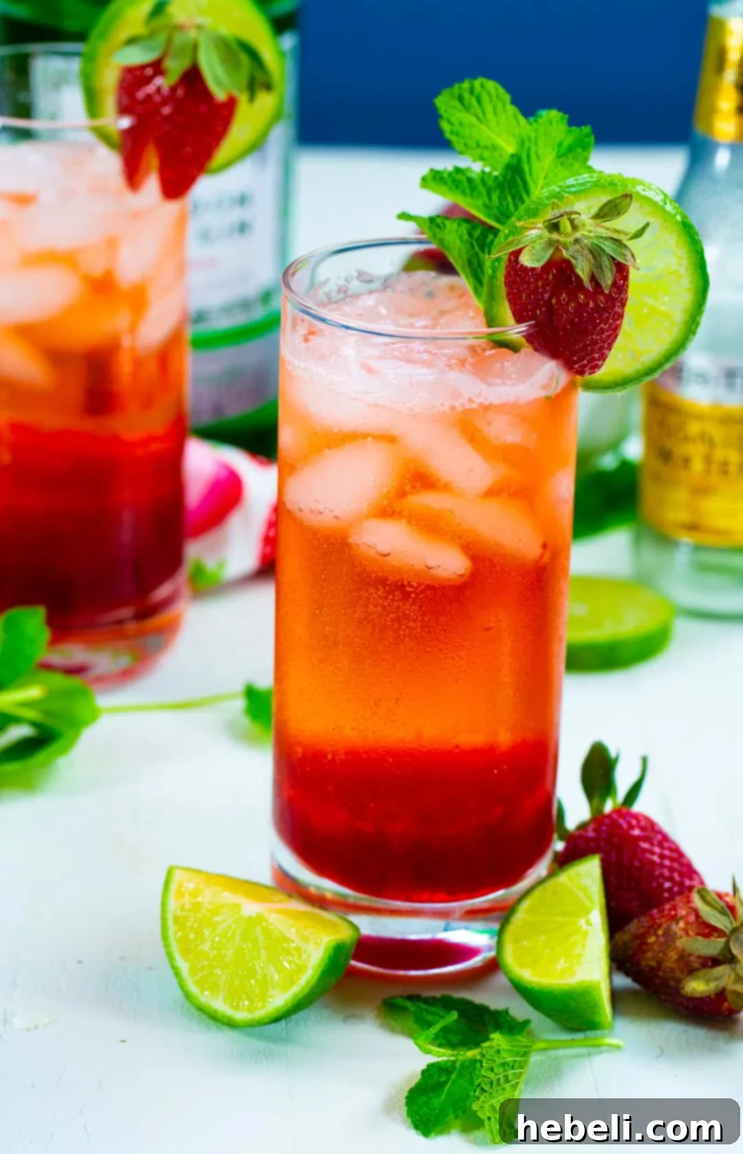 A tall glass of Strawberry Gin and Tonic, showcasing its beautiful color and garnished with fresh berries and a lime slice.