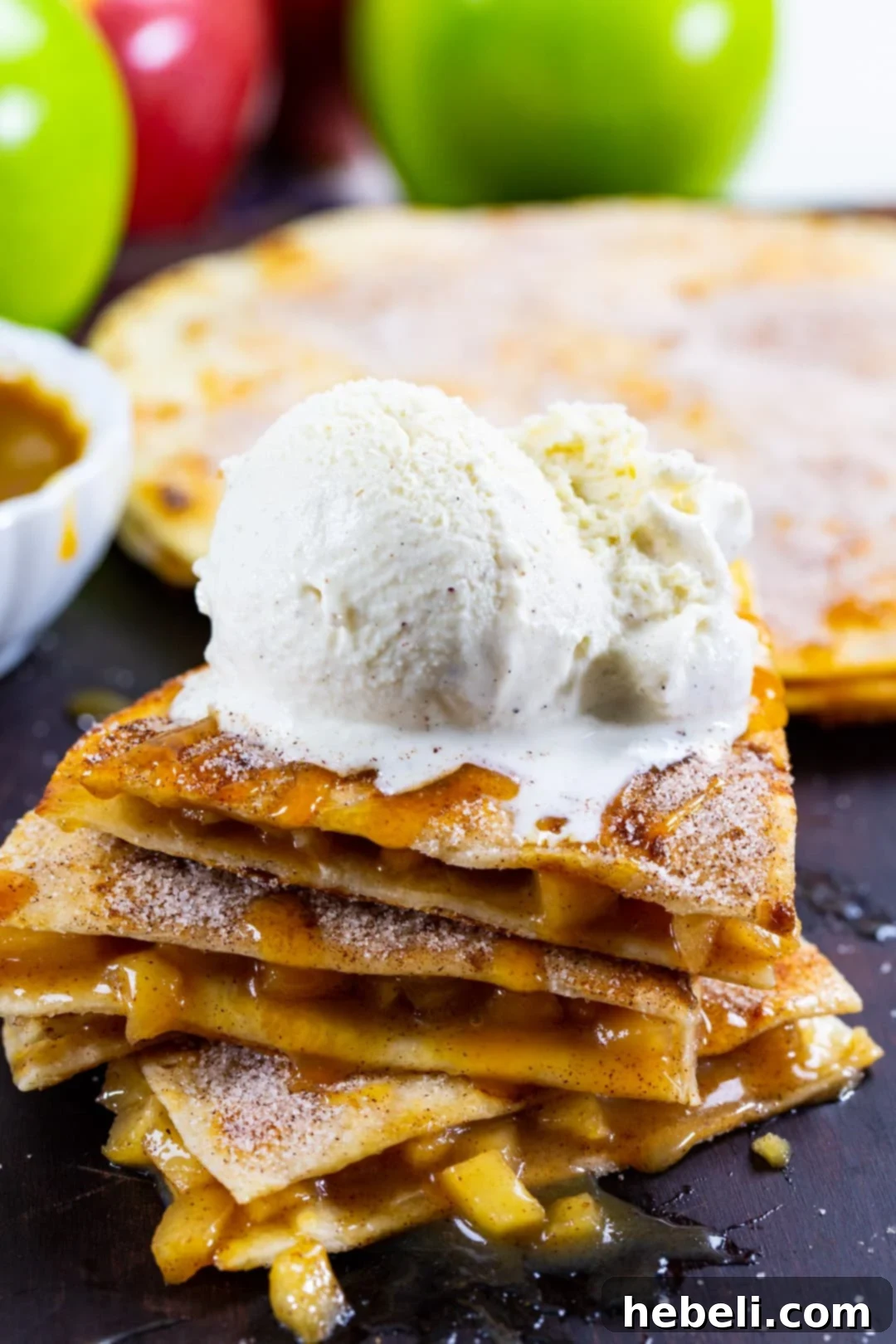 Stacked Caramel Apple Quesadillas, ready to be served, with vanilla ice cream and caramel sauce.