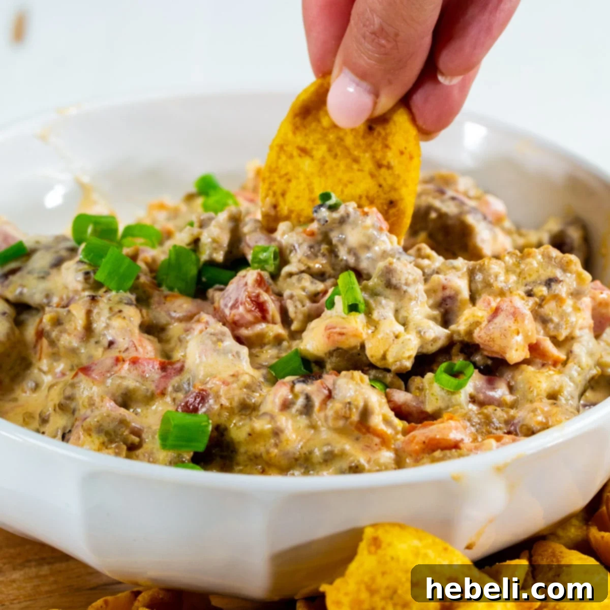Chip scooping up creamy 3-Ingredient Sausage Rotel Dip, highlighting its texture and inviting presentation.
