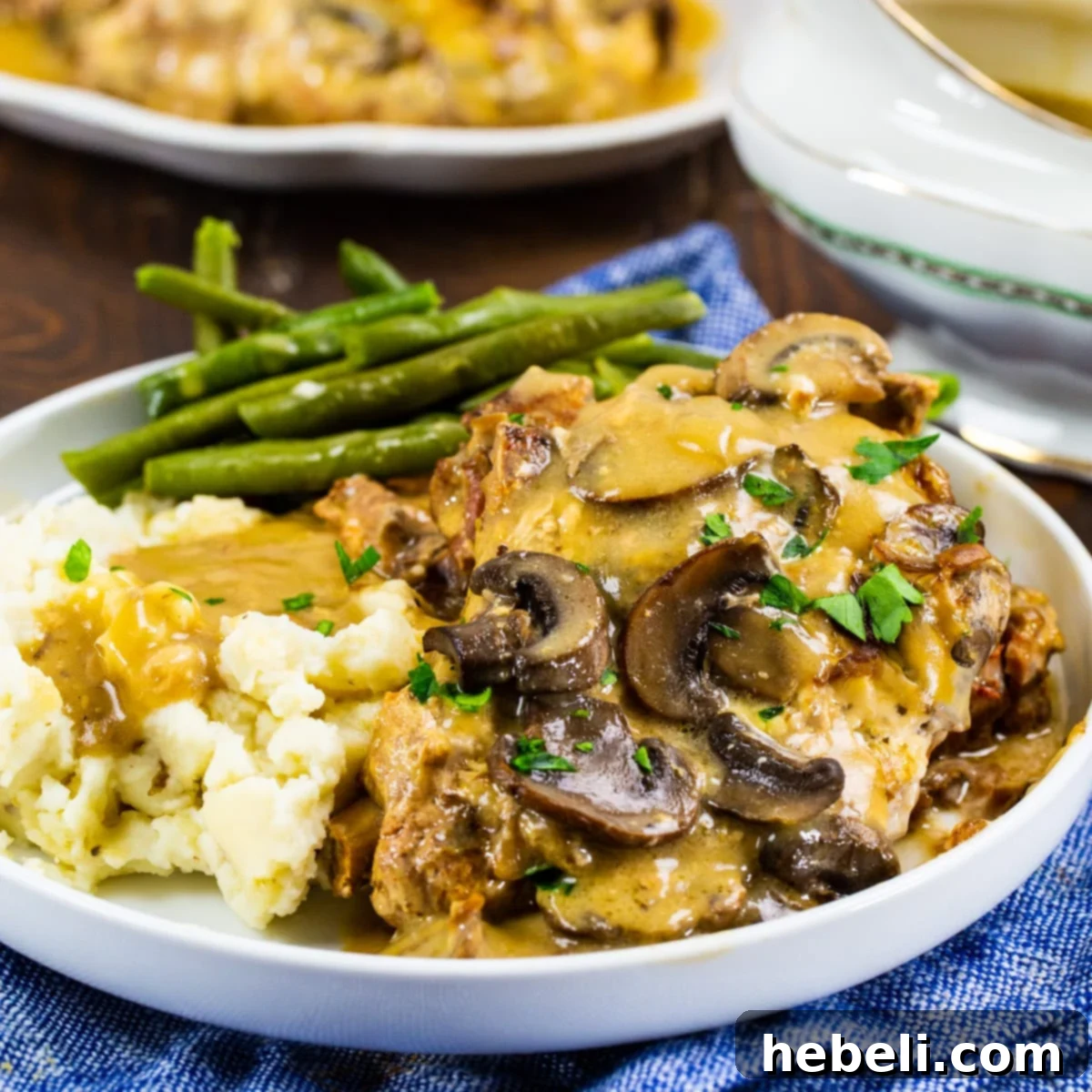 Slow Cooker Mushroom and Onion Pork Chops on plate with mashed potatoes and green beans.
