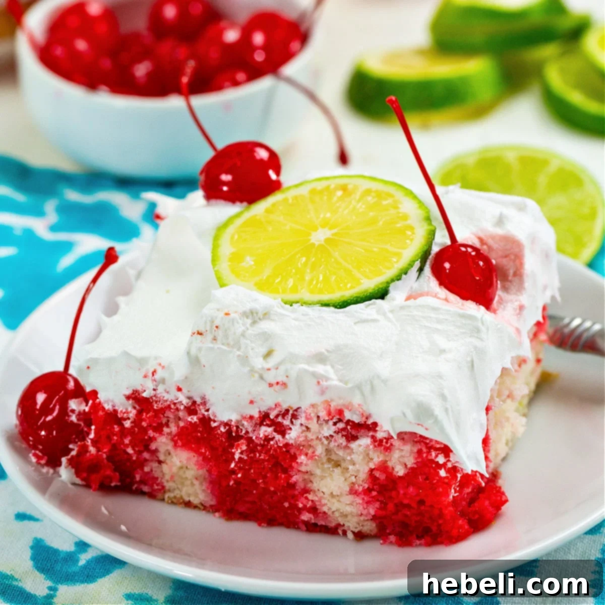 A vibrant slice of Cherry Limeade Poke Cake on a white plate, showcasing its red and white layers.